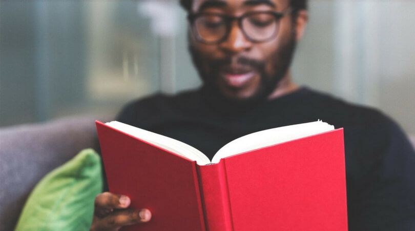 Man with eyeglasses reading red book